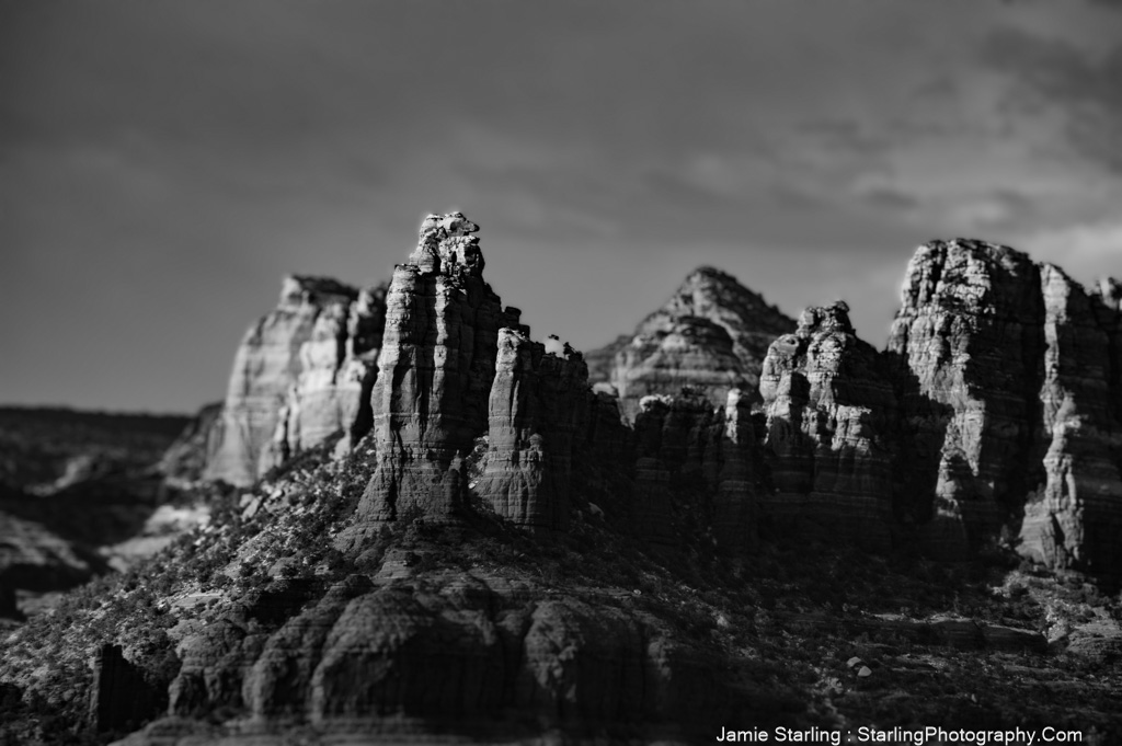 A serene black and white image of ancient rock formations reaching towards the sky, symbolizing the quest for inner peace in the midst of life's unceasing flow.