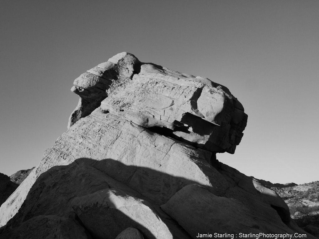 A black and white photograph capturing a majestic rock formation, each angle offering a unique perspective that invites viewers to reconsider their views on life’s challenges and opportunities.