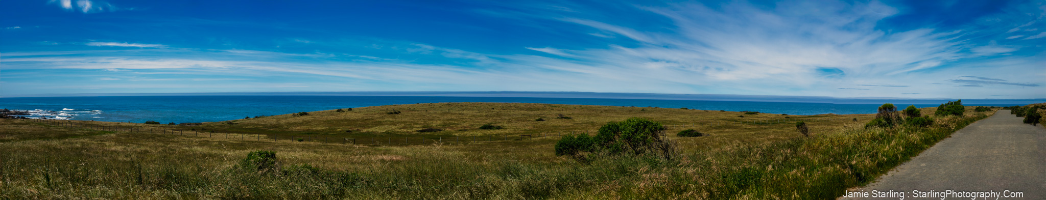 A beautiful coastal meadow with a clear blue sky and the sea in the distance, symbolizing life's journey, dreams, and the clarity and peace we seek.