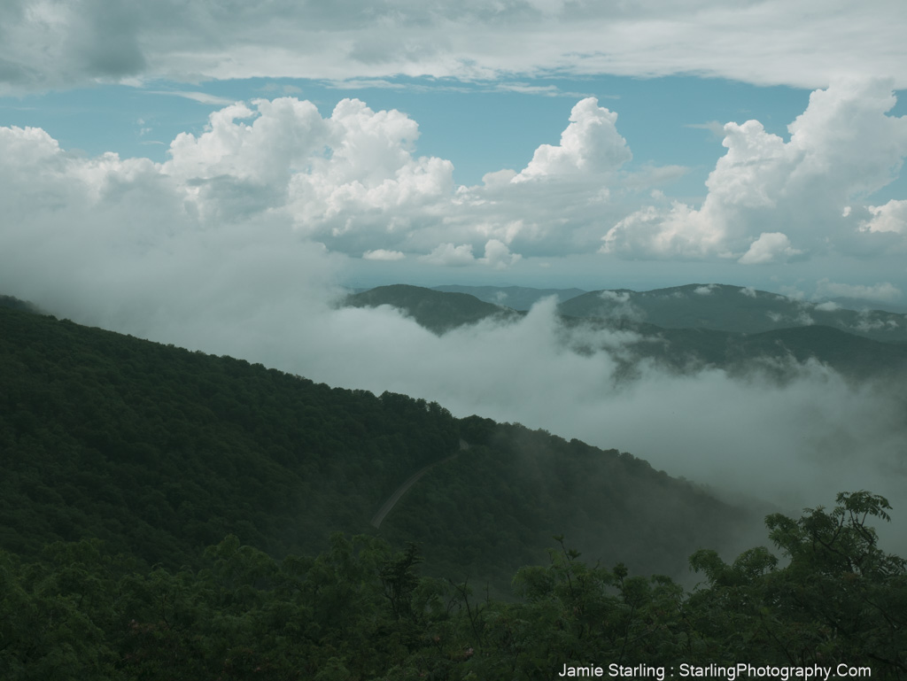 A misty landscape with a winding road through rolling hills, evoking a sense of mystery and the exploration of deeper realities beyond the visible.