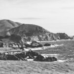 A captivating black-and-white coastal landscape with rugged cliffs and serene ocean waves, symbolizing the journey of life and the beauty in both calm and tumultuous moments.