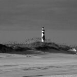 A lighthouse stands tall on a windswept beach, symbolizing inner strength and guidance through life's storms.