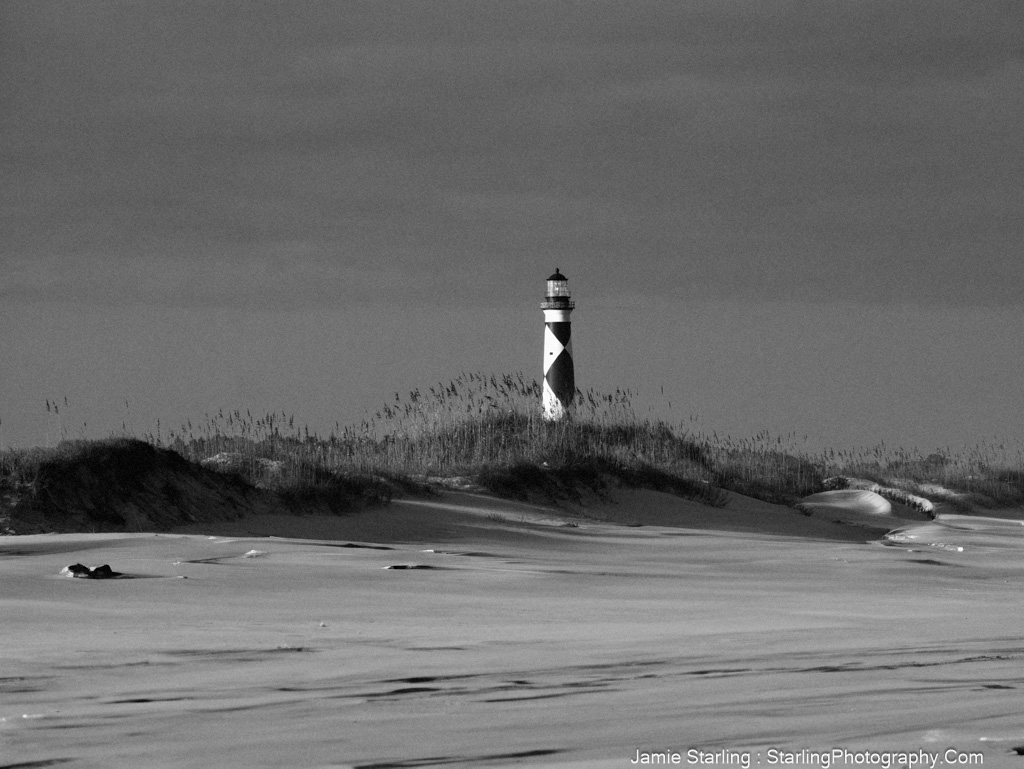 A lighthouse stands tall on a windswept beach, symbolizing inner strength and guidance through life's storms.