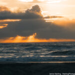 Sunlight breaking through dark clouds over the ocean, symbolizing the journey from external guidance to personal wisdom.