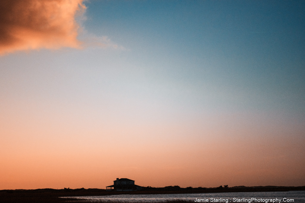 A solitary house under a vast, colorful sky, symbolizing the smallness of the ego compared to the limitless nature of our true self, inviting viewers to reflect on their own journey beyond the ego.