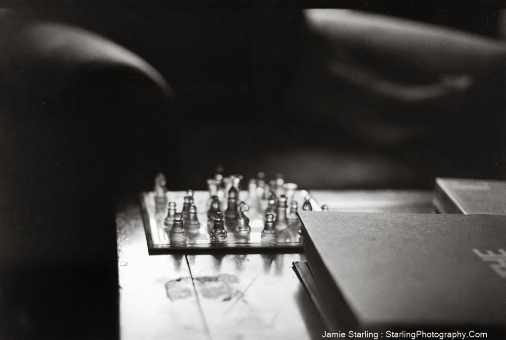 A glass chessboard with pieces in soft light and shadow, symbolizing the thoughtful and introspective decisions an artist faces on their creative journey.