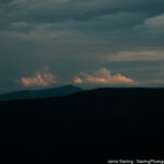 A mountain range in darkness with soft light on distant clouds, symbolizing the journey from fear to understanding through the acquisition of knowledge.