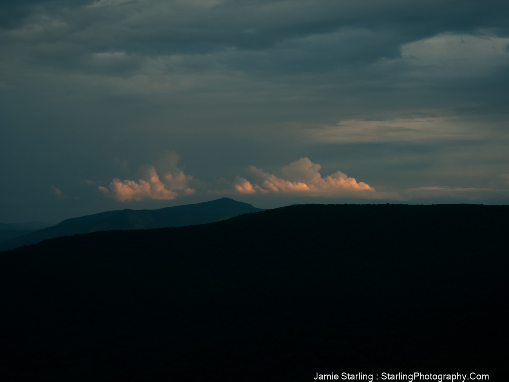 A mountain range in darkness with soft light on distant clouds, symbolizing the journey from fear to understanding through the acquisition of knowledge.