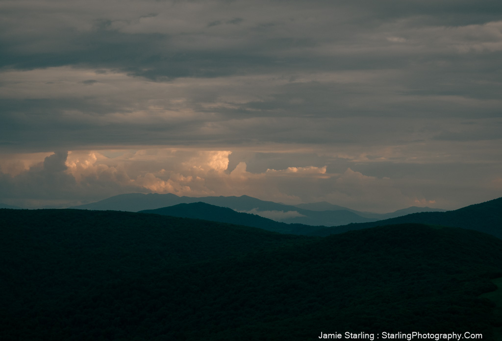 Layered mountains with light breaking through the clouds, symbolizing the journey to uncover the true self and find clarity within.