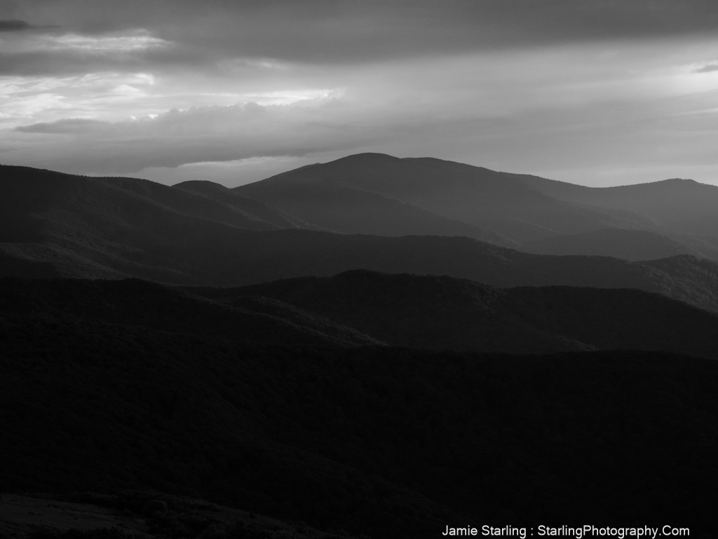 Darkened mountain ranges with light breaking through clouds, symbolizing the journey from belief in external authority to discovering the power within.