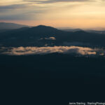 A tranquil mountain range at dawn with soft light and lingering mist, symbolizing the journey of waking up to your own creative vision in photography.