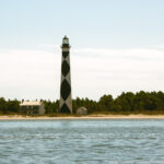 A tall lighthouse on a serene shoreline, symbolizing the power of photography to question conformity and reveal deeper truths.