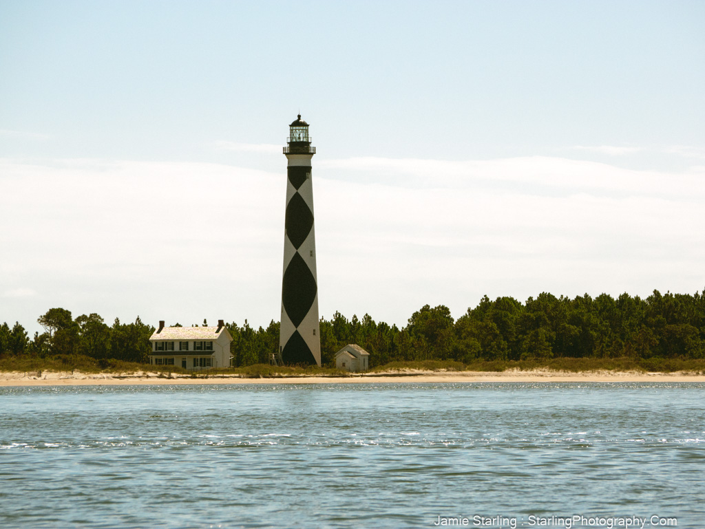 A tall lighthouse on a serene shoreline, symbolizing the power of photography to question conformity and reveal deeper truths.