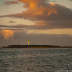 A tranquil sunset scene with a lighthouse on a small island, surrounded by calm waters and a sky painted with soft, warm hues, symbolizing resilience and guidance in everyday life.