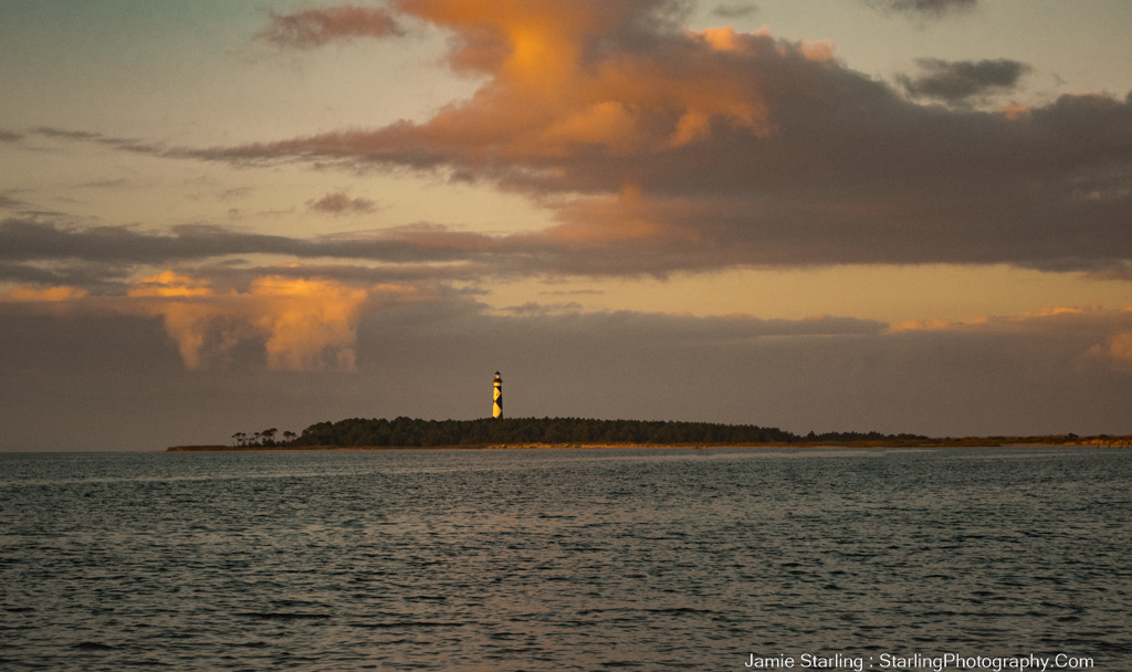 A tranquil sunset scene with a lighthouse on a small island, surrounded by calm waters and a sky painted with soft, warm hues, symbolizing resilience and guidance in everyday life.