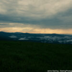 Tranquil dusk over rolling hills with low-lying clouds, symbolizing emotional depth and the journey of self-discovery in photography.