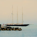 Sailboat resting by a breakwater under a calm sky, evoking a sense of tranquility and balance, inviting viewers to pause and reflect.