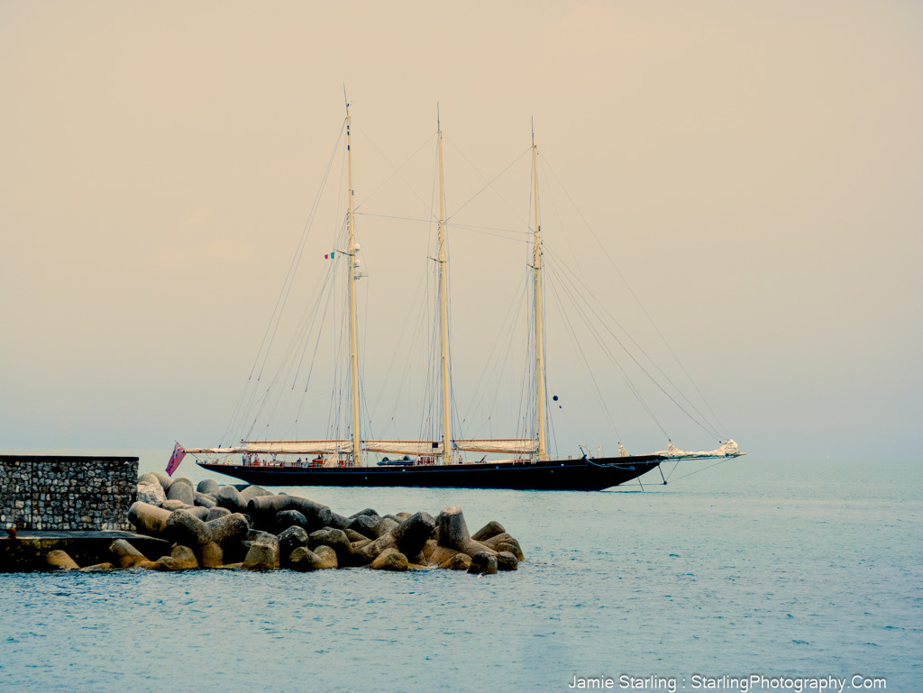 Sailboat resting by a breakwater under a calm sky, evoking a sense of tranquility and balance, inviting viewers to pause and reflect.