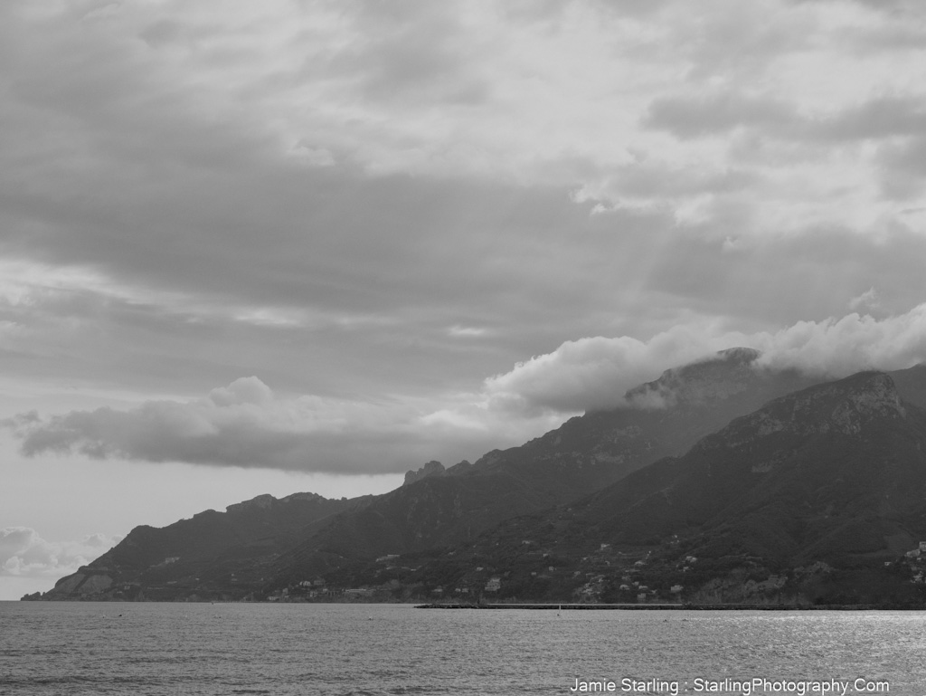 A black and white photo of misty mountains against a soft sky, inviting a moment of reflection and appreciation for the beauty in subtle details.