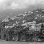 A misty mountainside village with homes rising toward the clouds, symbolizing life’s journey of balance, growth, and connection.