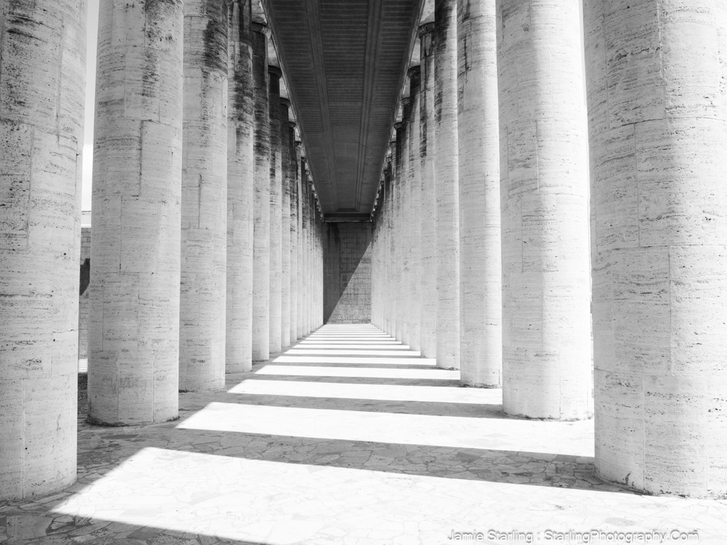 A serene architectural photo of columns and shadows, creating a sense of calm and inviting viewers to pause and reflect.