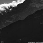 A black-and-white photo of rugged mountains with light breaking through mist, creating a dramatic contrast between light and shadow.